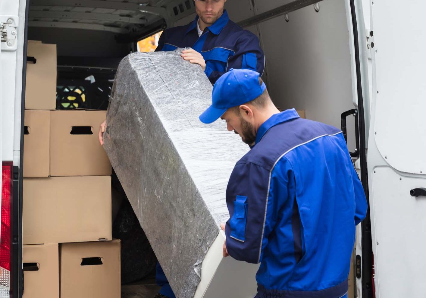 Two Delivery Men Unloading Furniture From Vehicle. Two Young Delivery Men In Uniform Unloading Furniture From Vehicle Belfast | County Down | County Antrim